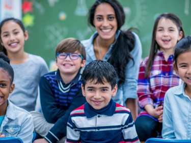 Group of children and a teacher smiling for a picture