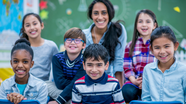 Group of children and a teacher smiling for a picture