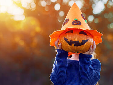 Child holding a jack-o-lantern in front of their face