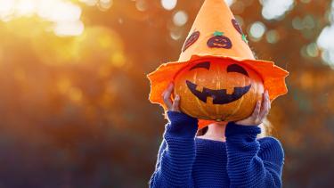 Halloween Child holding a jack-o-lantern in front of their face