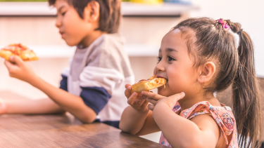 Hot lunch Girl and boy eating pizza