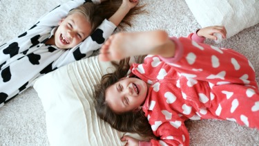 Two children laying on the floor with their pajamas on.