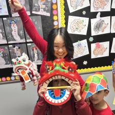 A teacher and a student wearing red with a paper dragon.
