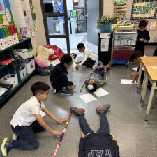 Students measuring another student using cubes