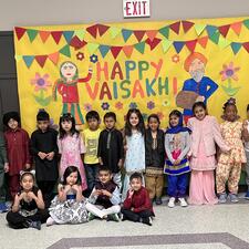 Students dressed up in front of a Happy Vaisakhi sign.