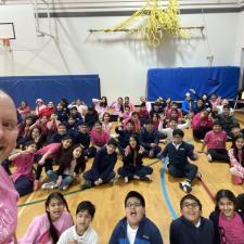 Students wearing pink shirts in a gym.