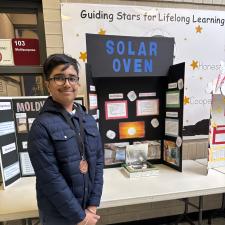 Student in front of a science fair project wearing a medal