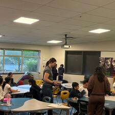 Students working at tables with two adults walking around.
