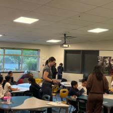 Students working at tables with two adults walking around.