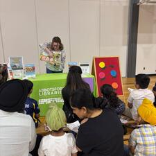 Parents and children listening to a presentation from the library.