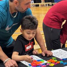 A young boy doing a puzzle with his dad.
