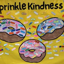 Three large donuts with sprinkles that have compliments on them.